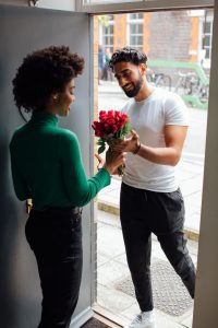 A woman answering the door to a man with flowers